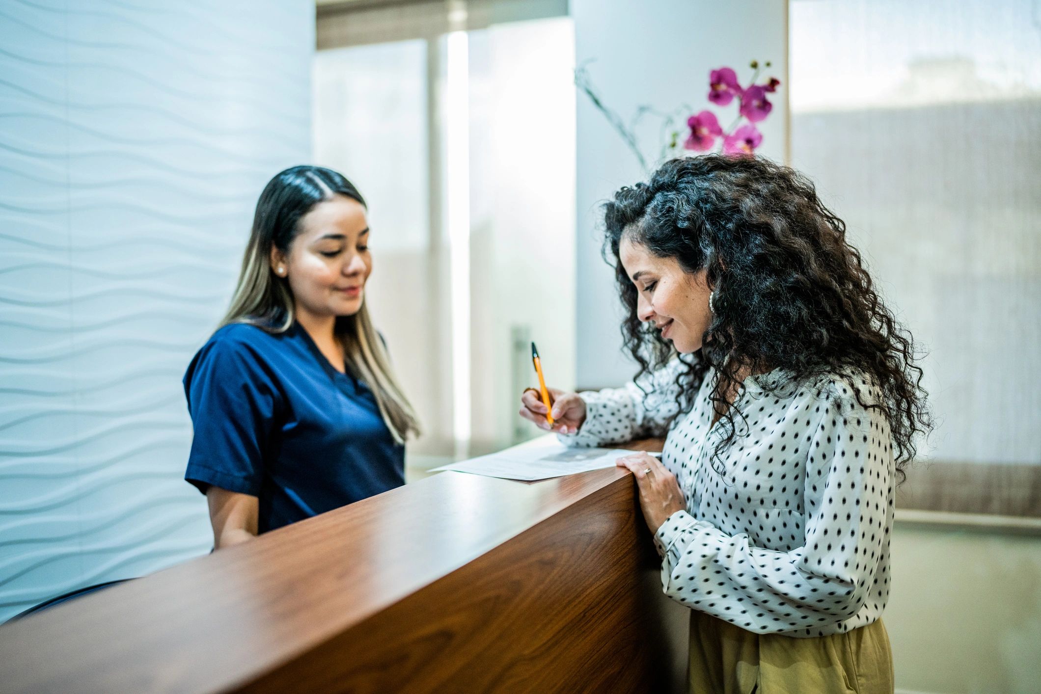 Patient speaking with staff at a dental clinic reception
